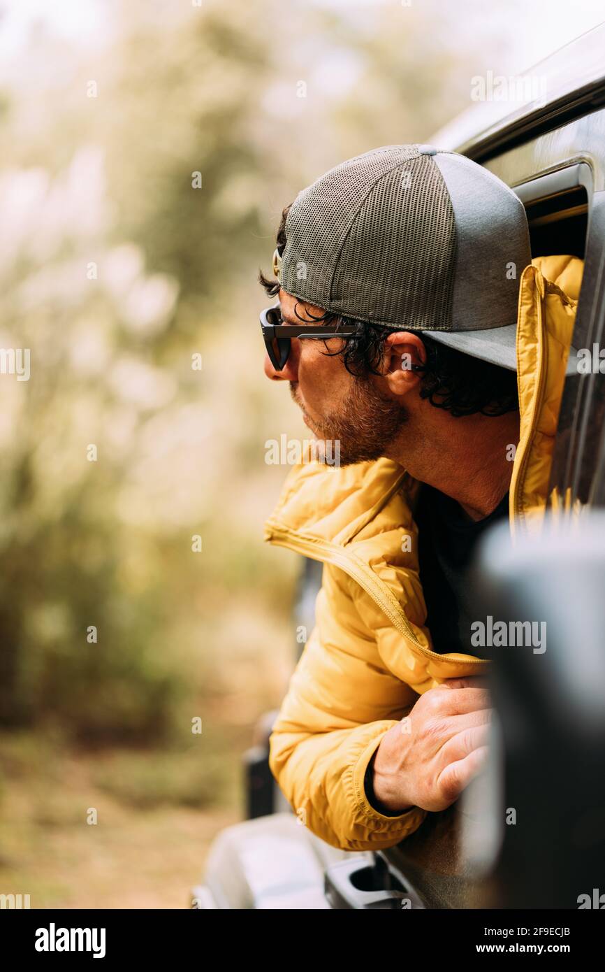 Vista lateral de un aventurero en una gorra y gafas de sol saliendo de la  venta de automóviles con un fondo borroso Fotografía de stock - Alamy