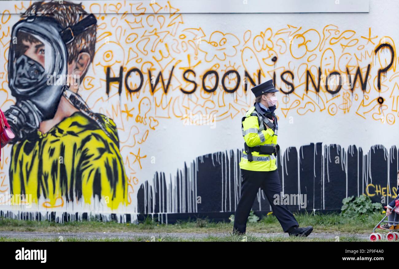 Un Garda pasa por un nuevo mural en el Grand Canal Docks de Dublín por el artista CHELS (Chelsea Jacobs), reflejando el incierto futuro de los niños debido a las restricciones de Covid-19. Fecha de la foto: Domingo 18 de abril de 2021. Foto de stock