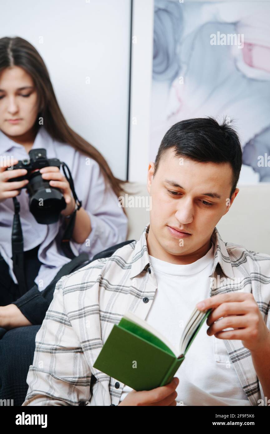 Tiempo libre de una pareja, está leyendo un libro, está mirando la pantalla Foto de stock