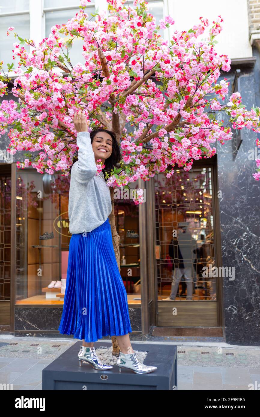 Un modelo con un jersey H&M gris con una falda larga de Anthropologie azul  y zapatos bershka plateados vistos durante una sesión de fotos de estilo  urbano en Bond Street, Londres Fotografía