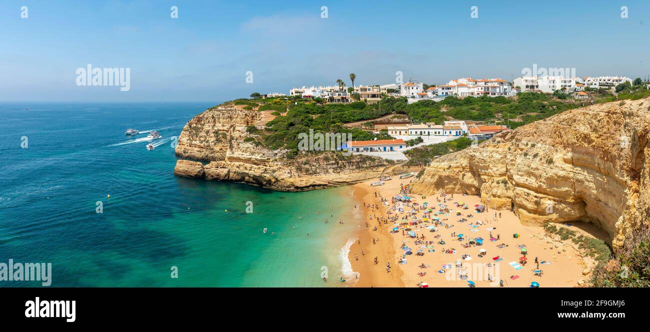 Vista de la playa de arena con bañistas, mar turquesa, Praia Benagil, escarpada costa de arenisca, formaciones rocosas en el mar, Algarve, Lagos, Portugal Foto de stock