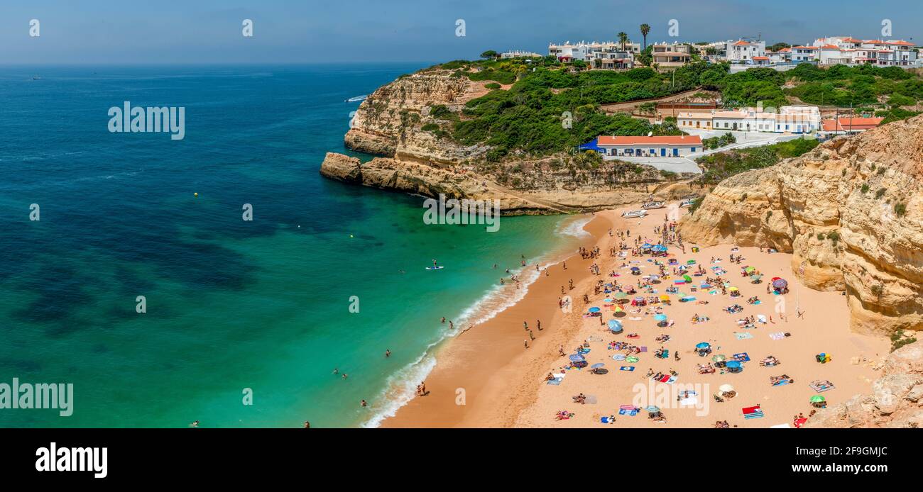Vista de la playa de arena con bañistas, mar turquesa, Praia Benagil, escarpada costa de arenisca, formaciones rocosas en el mar, Algarve, Lagos, Portugal Foto de stock