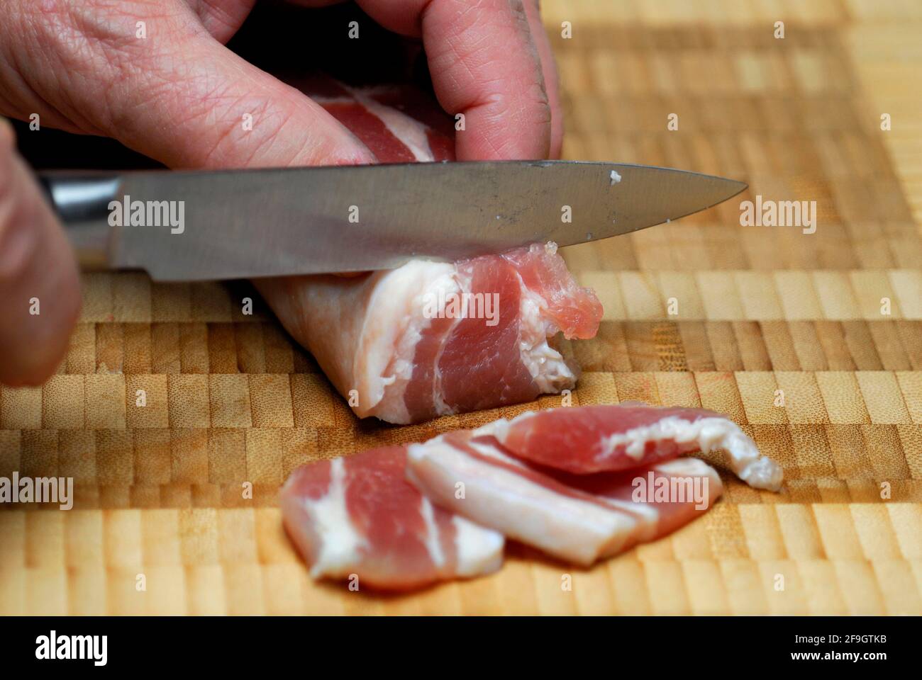 Tocino salado, se corta, tocino de cerdo, tocino curado, cuchillo, cortar Foto de stock