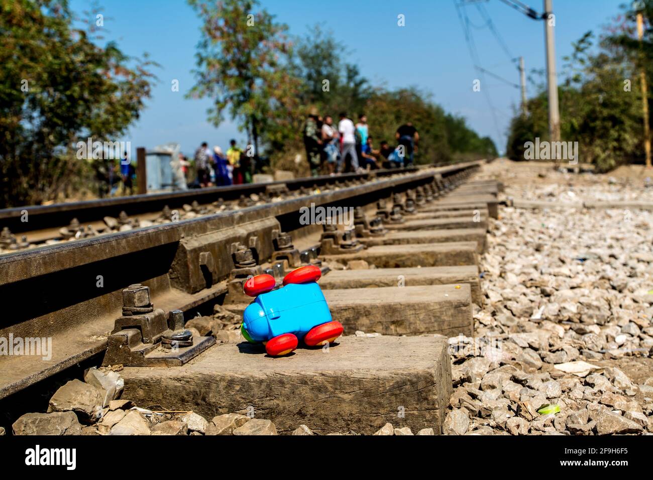 Primer plano del tren de juguete azul de un niño en el lateral de un ferrocarril con pequeñas rocas en el suelo Foto de stock
