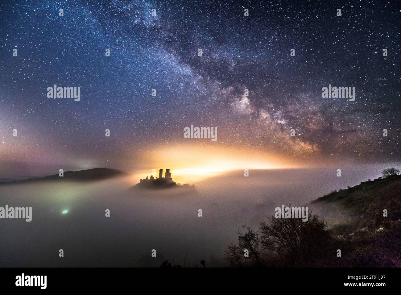Castillo de Corfe, Dorset, Reino Unido. 19th de abril de 2021. Clima del Reino Unido. La Vía Láctea brilla intensamente sobre el Castillo de Corfe en Dorset, que está rodeado por un denso mar de niebla en una noche fría y clara. Crédito de la foto: Graham Hunt/Alamy Live News Foto de stock