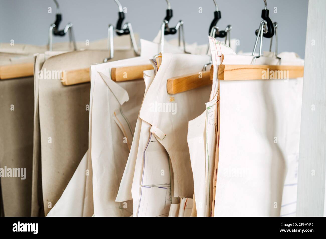 Muchos patrones de costura de papel para diferentes prendas colgadas en el  estante en el fondo de la fábrica de costura. Patrón de ropa, fabricación  en fábrica de costura Fotografía de stock 