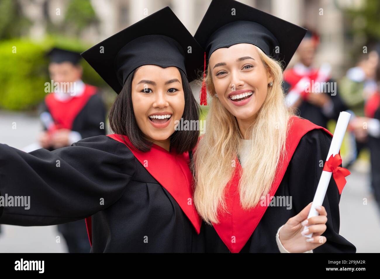 Felices mujeres jóvenes multirraciales en ropa de graduación tomando selfie  Fotografía de stock - Alamy