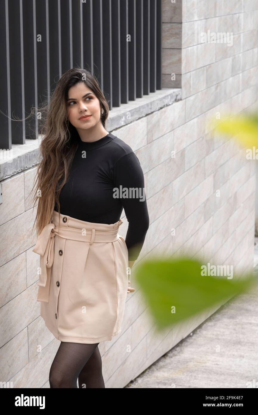 día soleado una atractiva mujer joven en la calle posando, ella lleva ropa  informal con una falda beige, mallas y blusa negra, estilo de vida  Fotografía de stock - Alamy