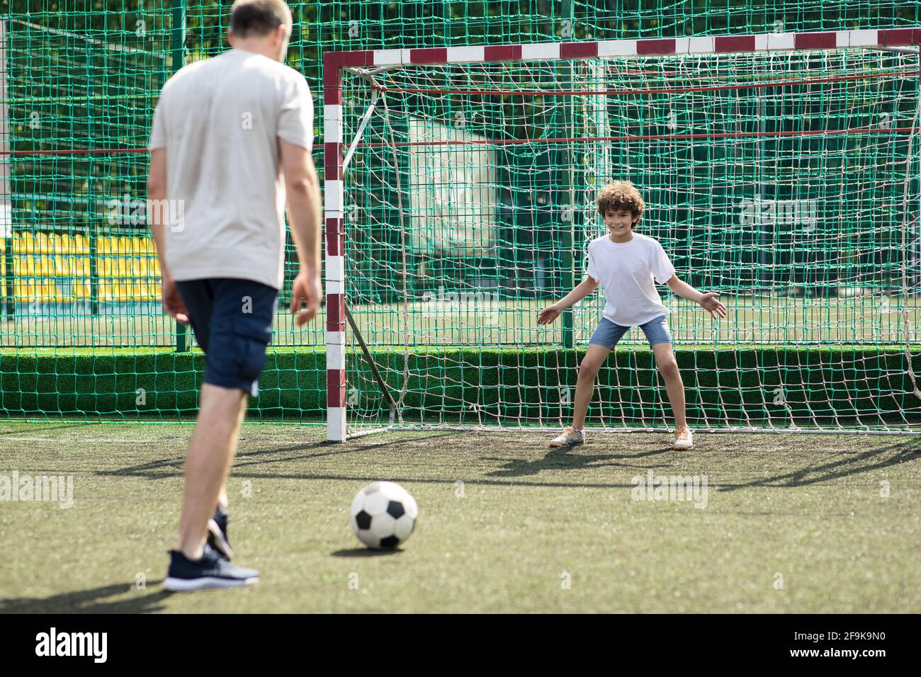 Hombre enseñando a su hijo a jugar al fútbol al aire libre Foto de stock