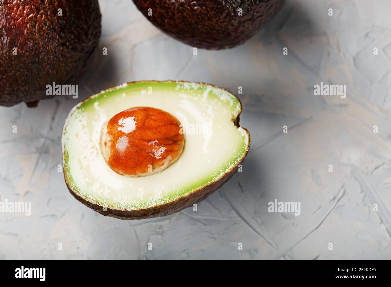 Aguacate Hass orgánico en rodajas y entero sobre fondo gris. Una fuente