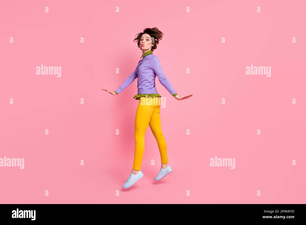 La foto del perfil de la longitud completa de la dama divertida salta para  arriba enviando los besos de aire usan pantalones de jersey zapatos  aislados color rosa fondo Fotografía de stock -