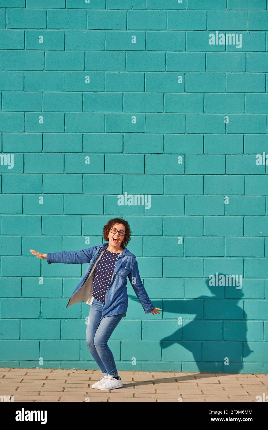 Vista frontal de una mujer feliz de pie contra una pared azul brillante en un día soleado. Fotografías de alta calidad. Foto de stock