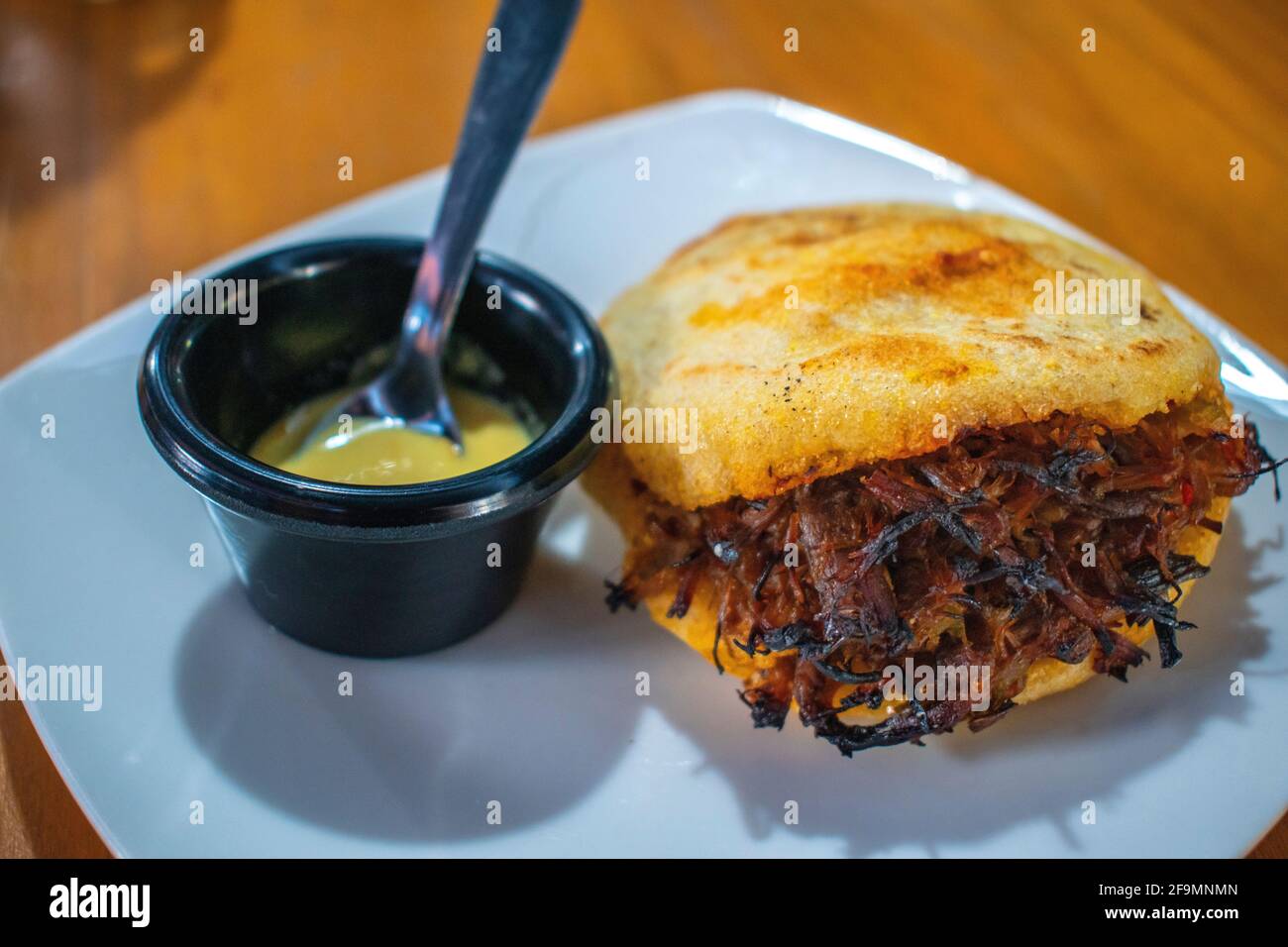 Arepa rellena de carne triturada con salsa picante. Foto de stock