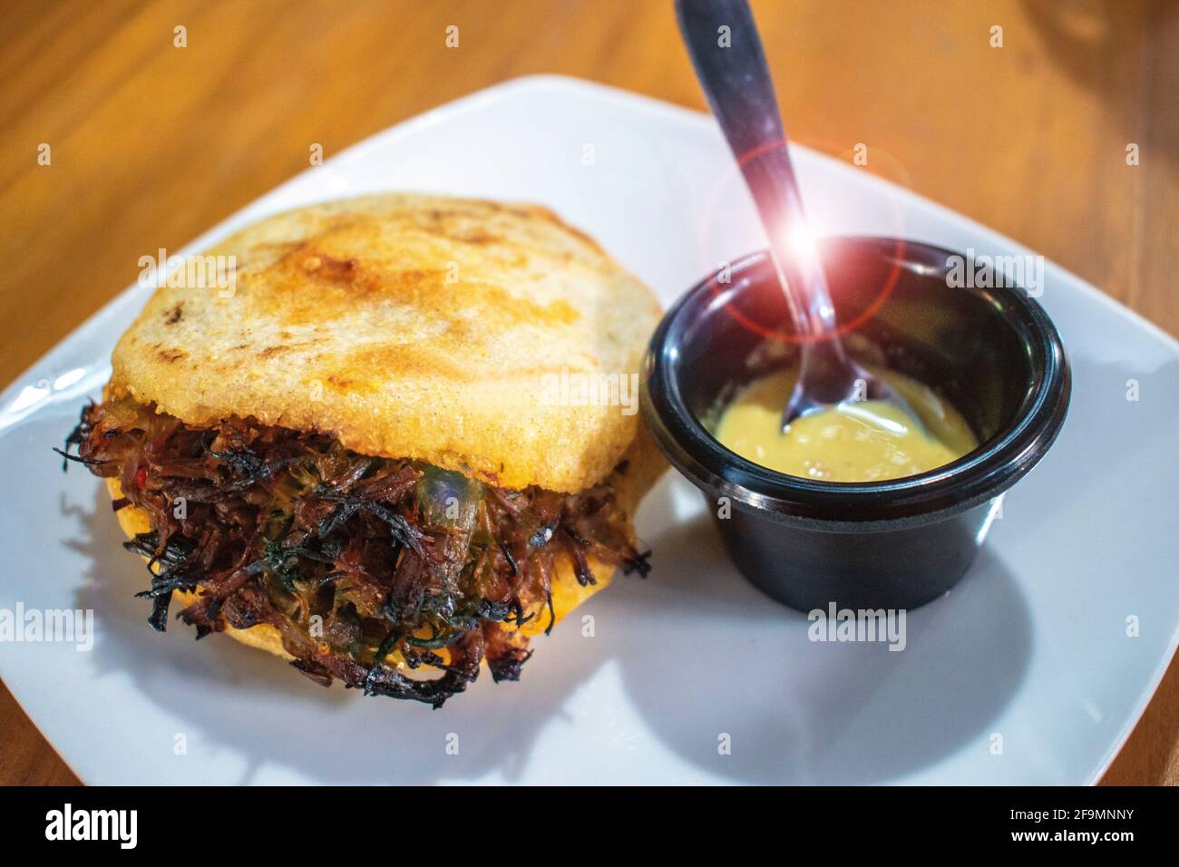 Arepa rellena de carne triturada con salsa picante. Foto de stock