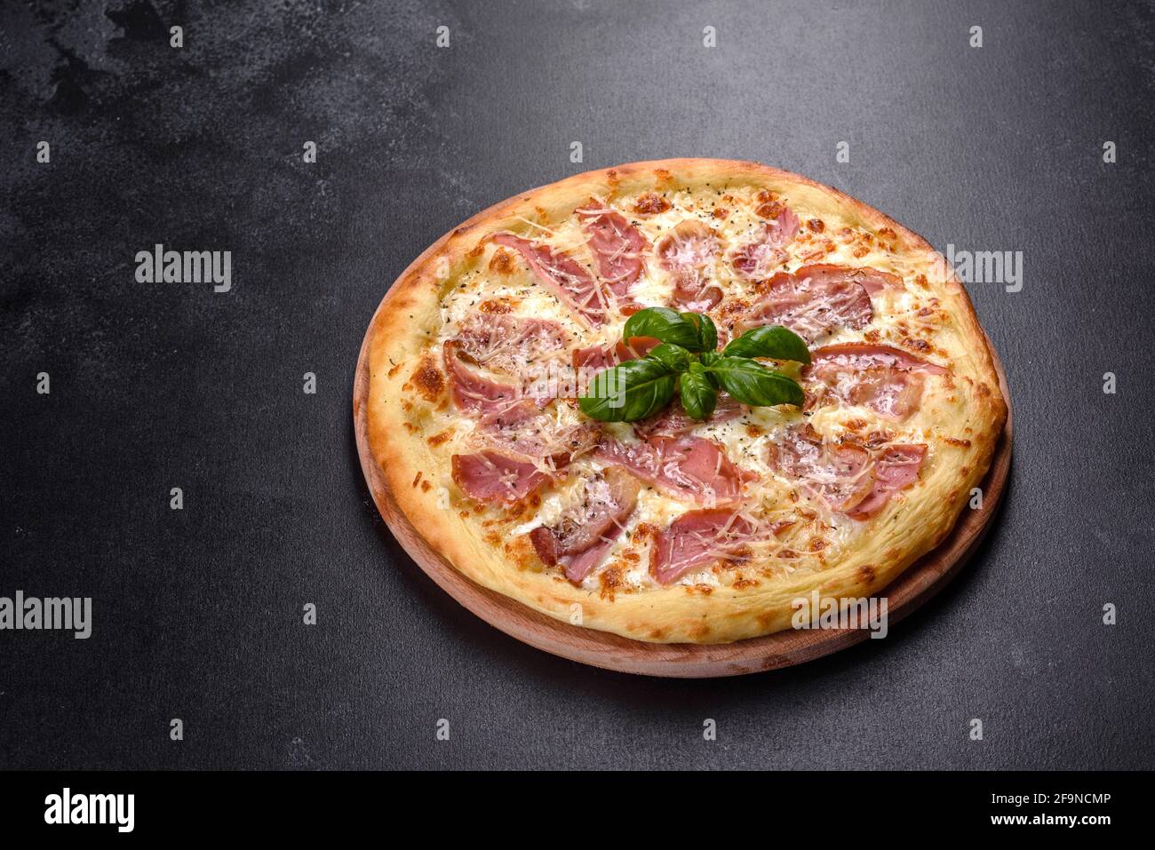 Deliciosa pizza crujiente fresca del horno con jamón, queso y albahaca.  Cocina italiana Fotografía de stock - Alamy