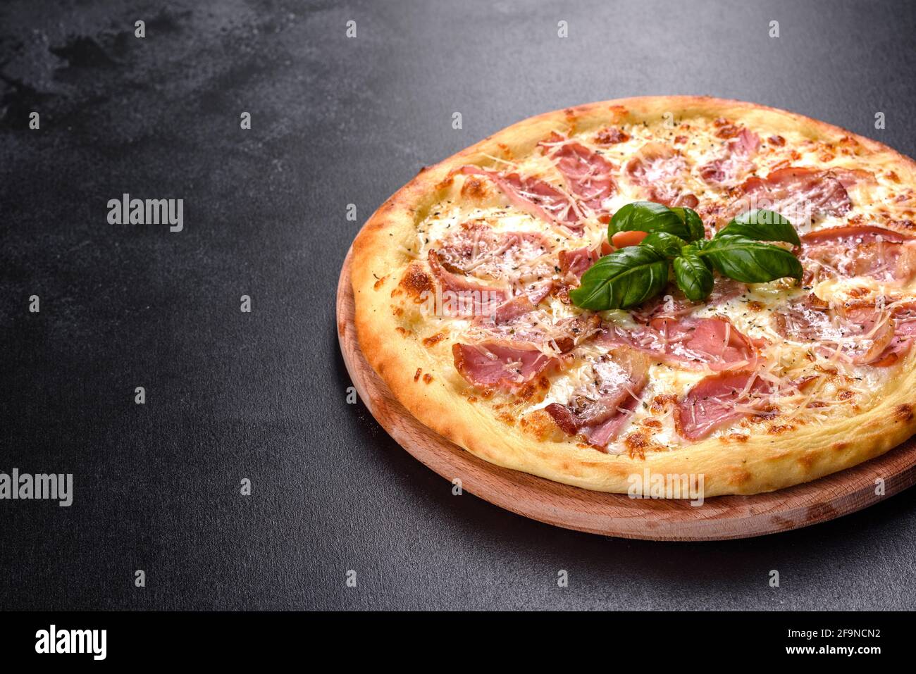 Deliciosa pizza crujiente fresca del horno con jamón, queso y albahaca.  Cocina italiana Fotografía de stock - Alamy