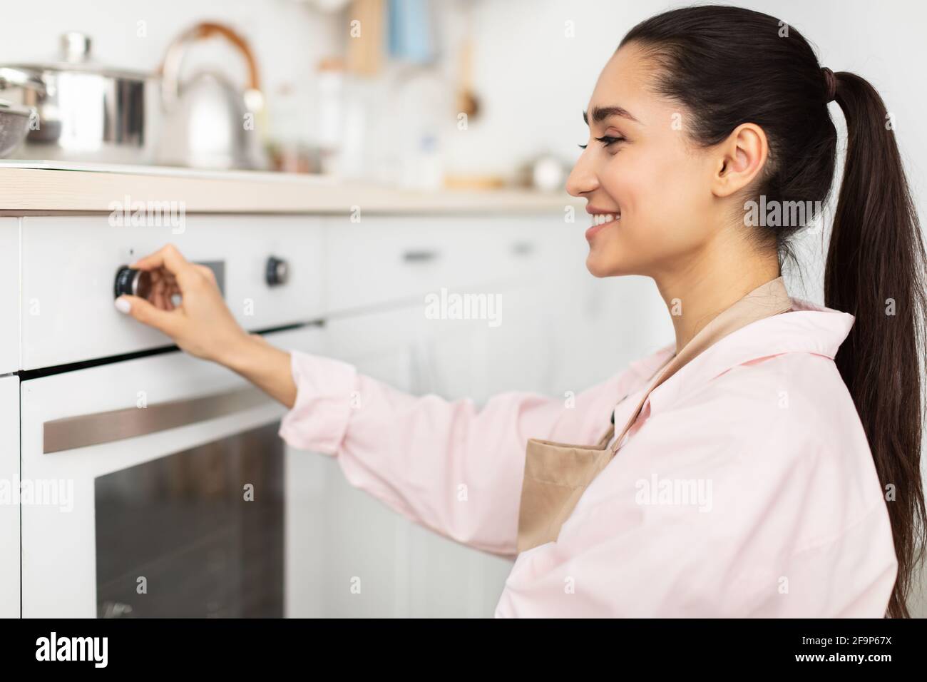 Mujer que usa cocina de cocina en la cocina Foto de stock