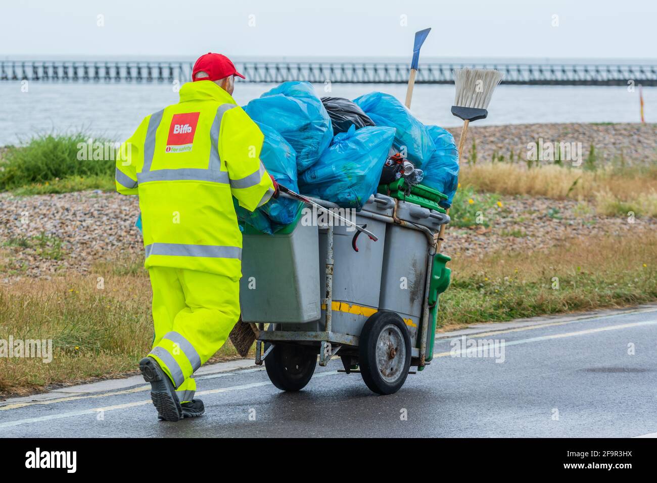 Trabajador de Biffa que empuja contenedores y recoge basura en el paseo marítimo de Littlehampton, West Sussex, Inglaterra, Reino Unido. Foto de stock