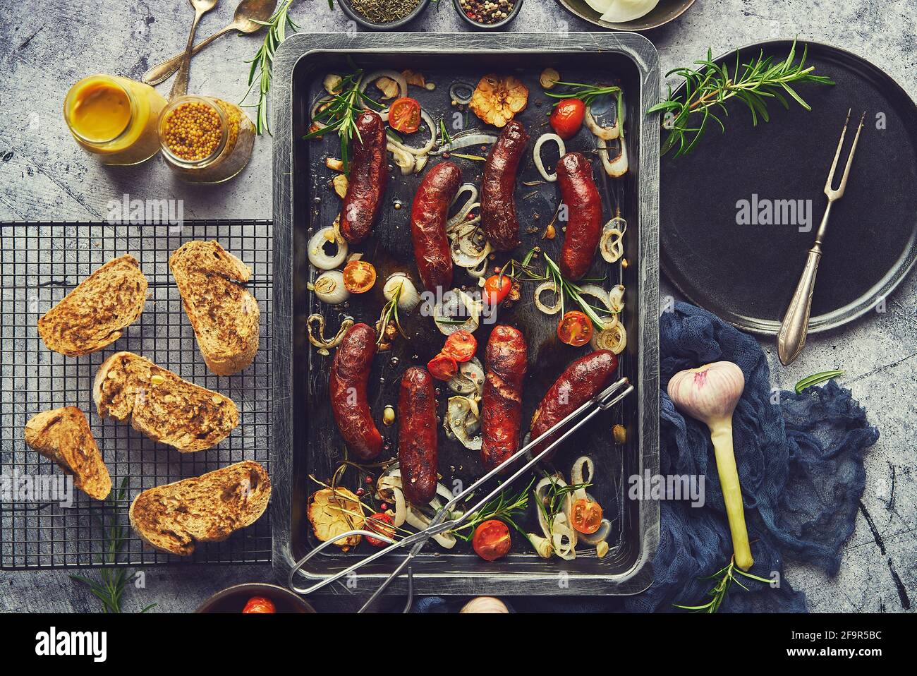 Deliciosas salchichas a la parrilla servidas en bandeja de metal oxidada con verduras a la barbacoa Foto de stock