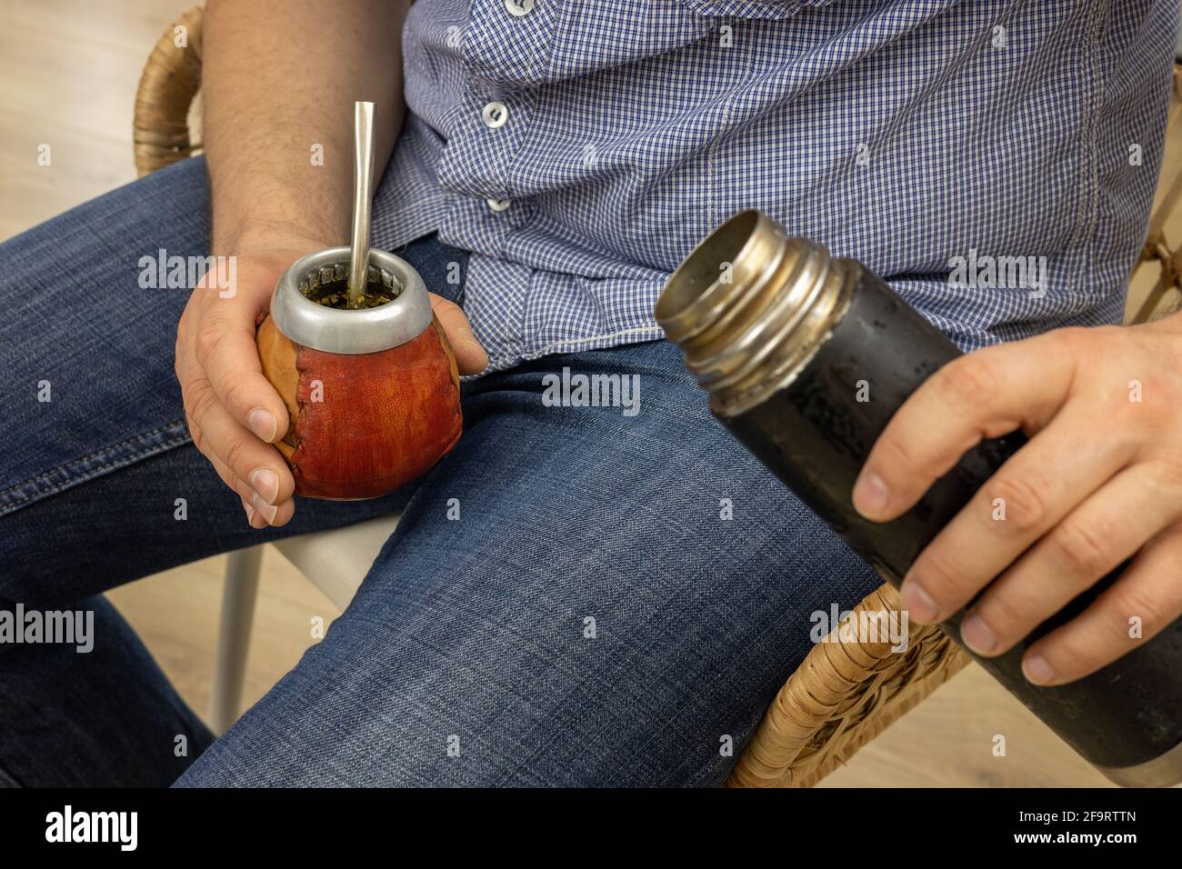 El hombre sentado vierte agua caliente de un termo a. Yerba mate Fotografía  de stock - Alamy