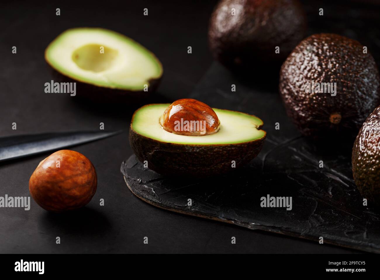 Aguacate orgánico entero y en rodajas Hass con un cuchillo sobre fondo