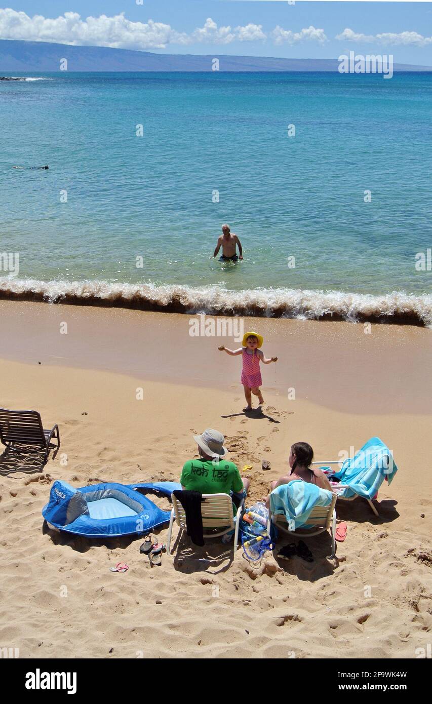 los turistas se relajan bajo sombrillas y nadan y juegan en el Playa arenosa y soleada kaanapali al oeste de la ciudad de Lahaina En la isla de Maui Hawaii usa Foto de stock