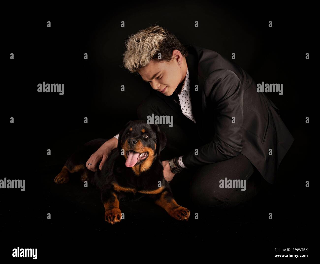 purebred rottweiler y adolescente frente al fondo negro Foto de stock