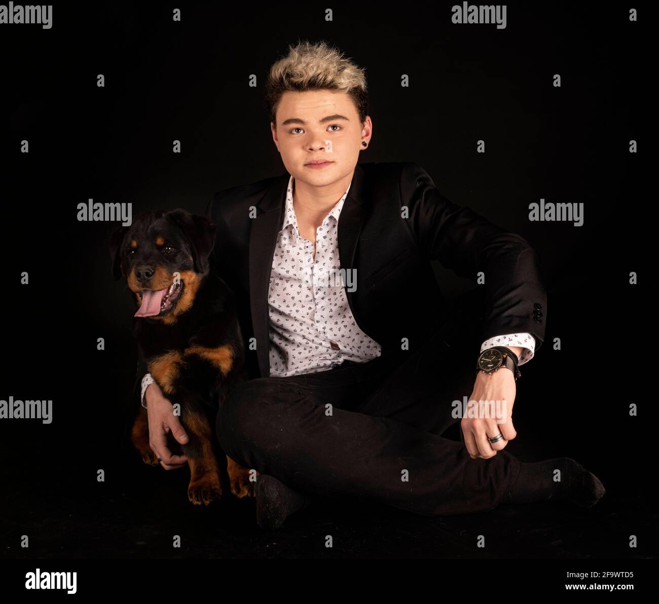 purebred rottweiler y adolescente frente al fondo negro Foto de stock