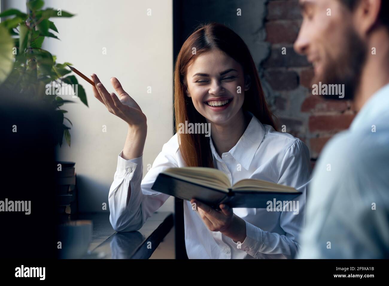 Mujer de negocios en camisa con libro en manos al lado trabajo de oficina Foto de stock