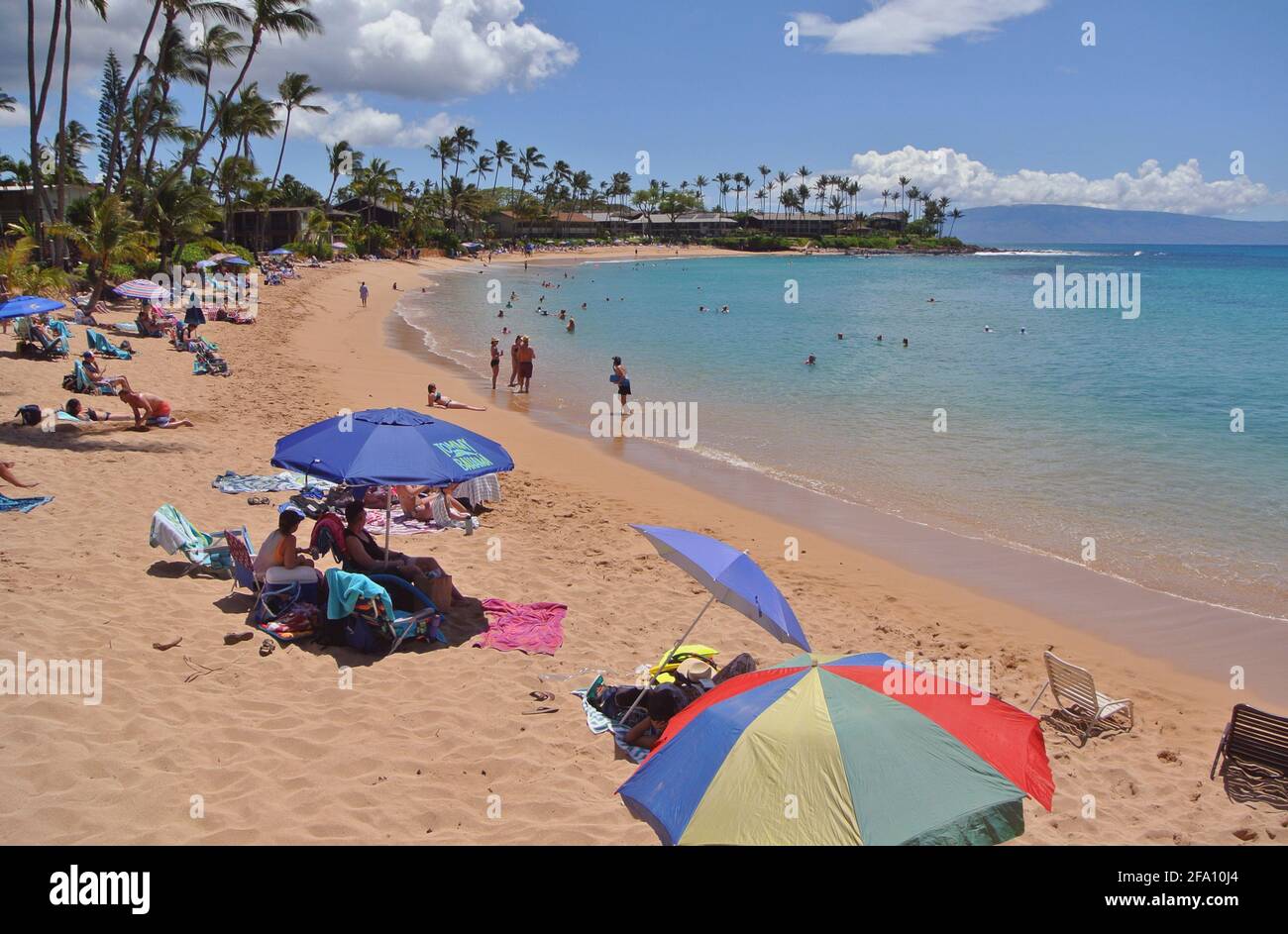 los turistas se relajan bajo sombrillas y nadan y juegan en el Playa arenosa y soleada kaanapali al oeste de la ciudad de Lahaina En la isla de Maui Hawaii usa Foto de stock