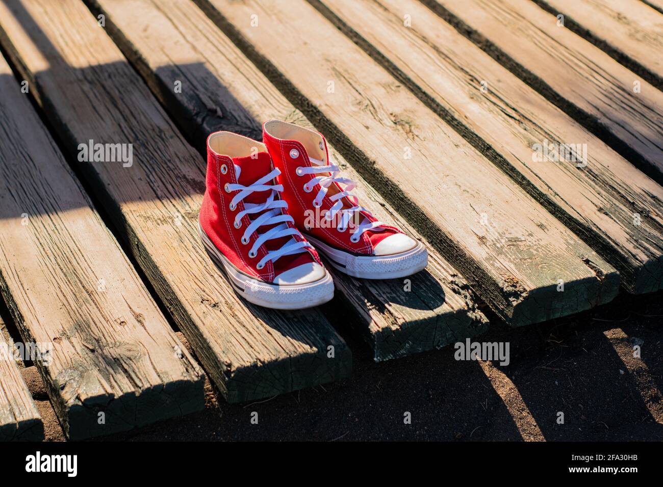Primer plano de un par zapatillas rojas para mujer, sobre una superficie de madera sobre la arena de la playa Fotografía de stock - Alamy