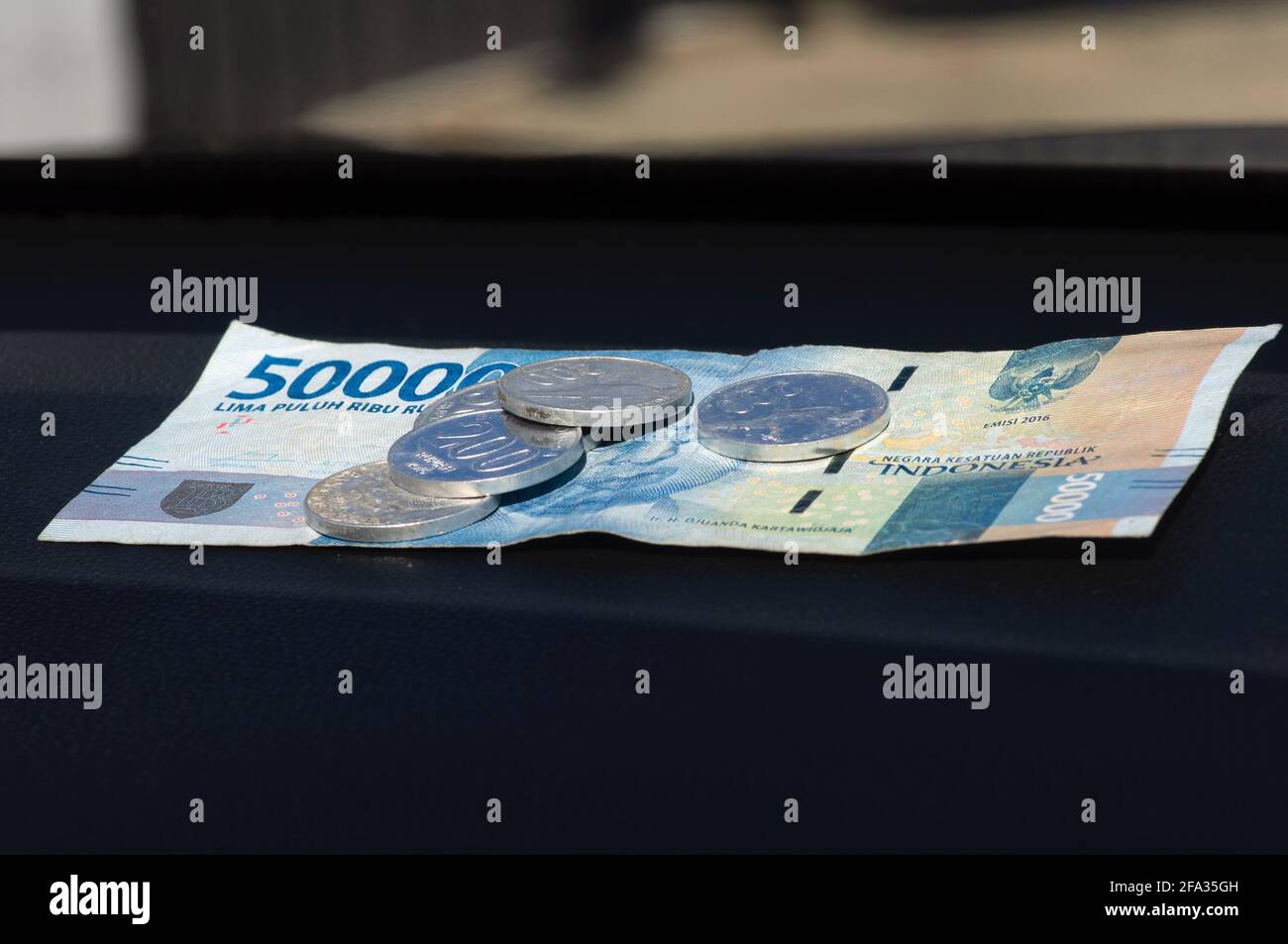 50000 Moneda indonesia de Rupiah y algunas monedas de Rupiah, sobre la mesa oscura Foto de stock