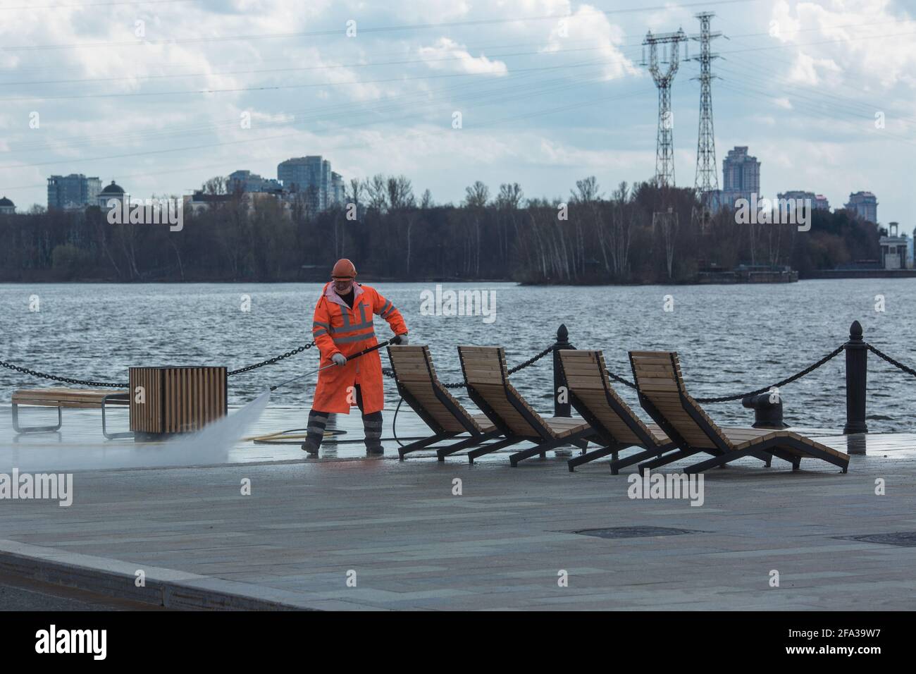 Moscú, Rusia - 22 2021 de abril: Trabajador municipal que limpia el terraplén utilizando equipos de agua a alta presión. Foto de stock