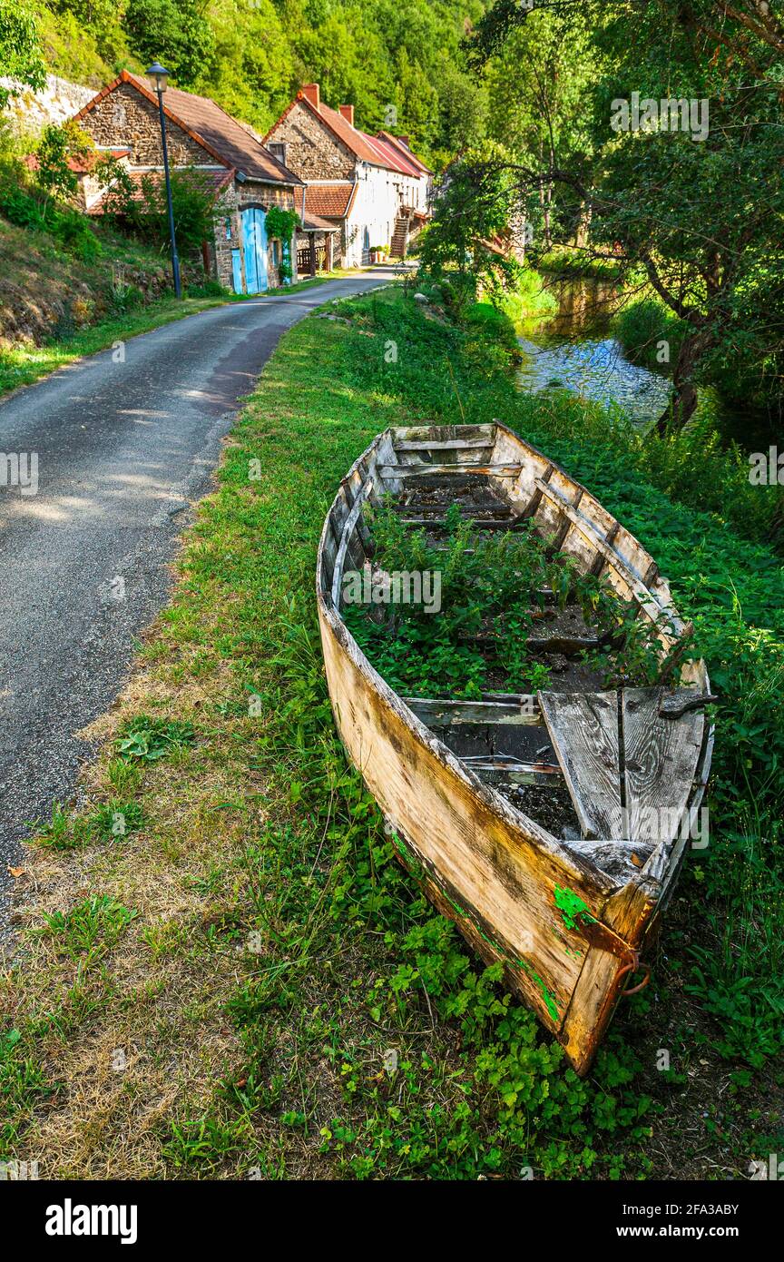 Menat es un pueblo francés a orillas del río Sioule. Un barco ahora inutilizable amarrado en la orilla del río. Puy-de-Dôme, Francia Foto de stock
