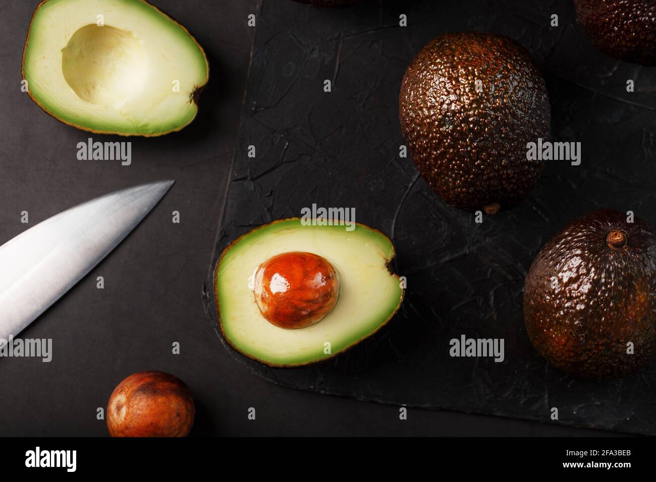 Aguacate orgánico entero y en rodajas Hass con un cuchillo sobre fondo