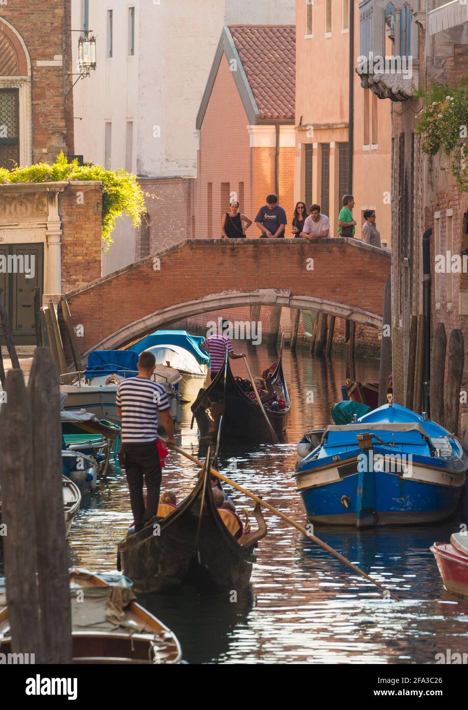 Venecia, Provincia de Venecia, Región del Véneto, Italia. Gente en puente viendo las góndolas acercándose. Venecia y su laguna son Patrimonio de la Humanidad de la UNESCO Foto de stock