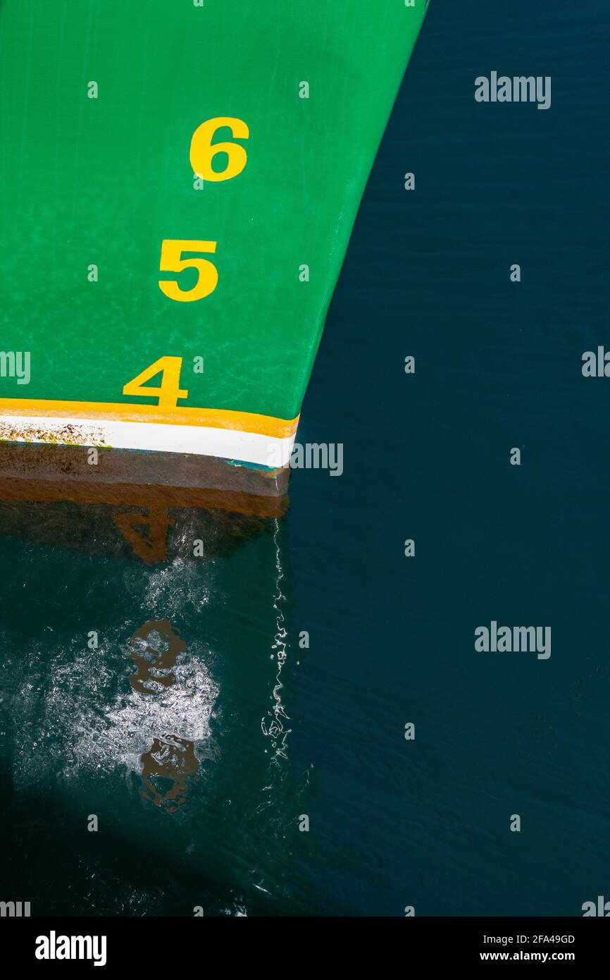 El arco de un gran barco verde con rayas marrones y blancas en la línea de agua con los números 3,4,5 y 6 en letras amarillas. Foto de stock