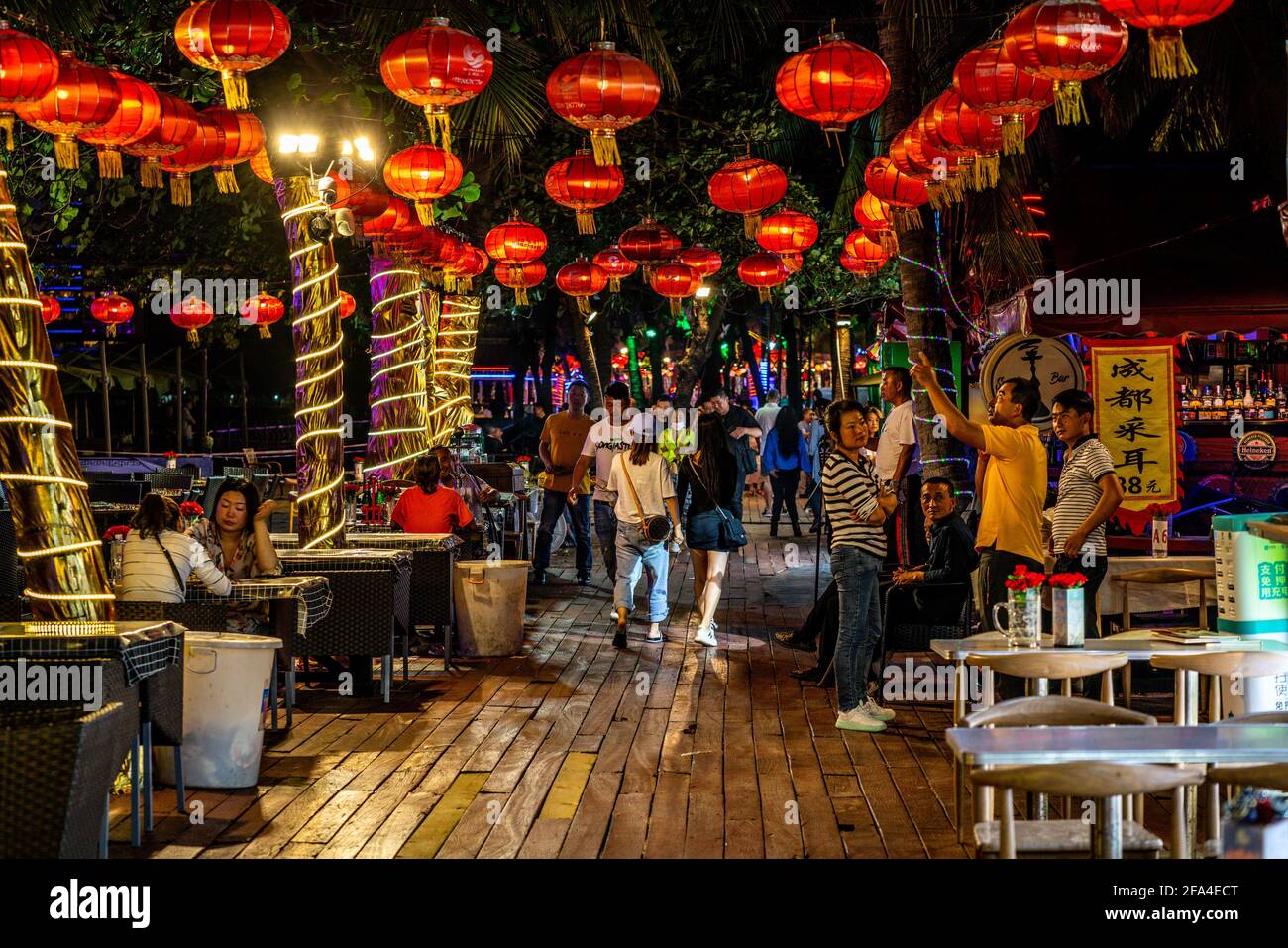 Sanya China , 25 de marzo de 2021 : Galería de la playa de Dadonghai por la noche con restaurante y bar terrazas con la gente en la ciudad de Sanya, isla de Hainan, China Foto de stock