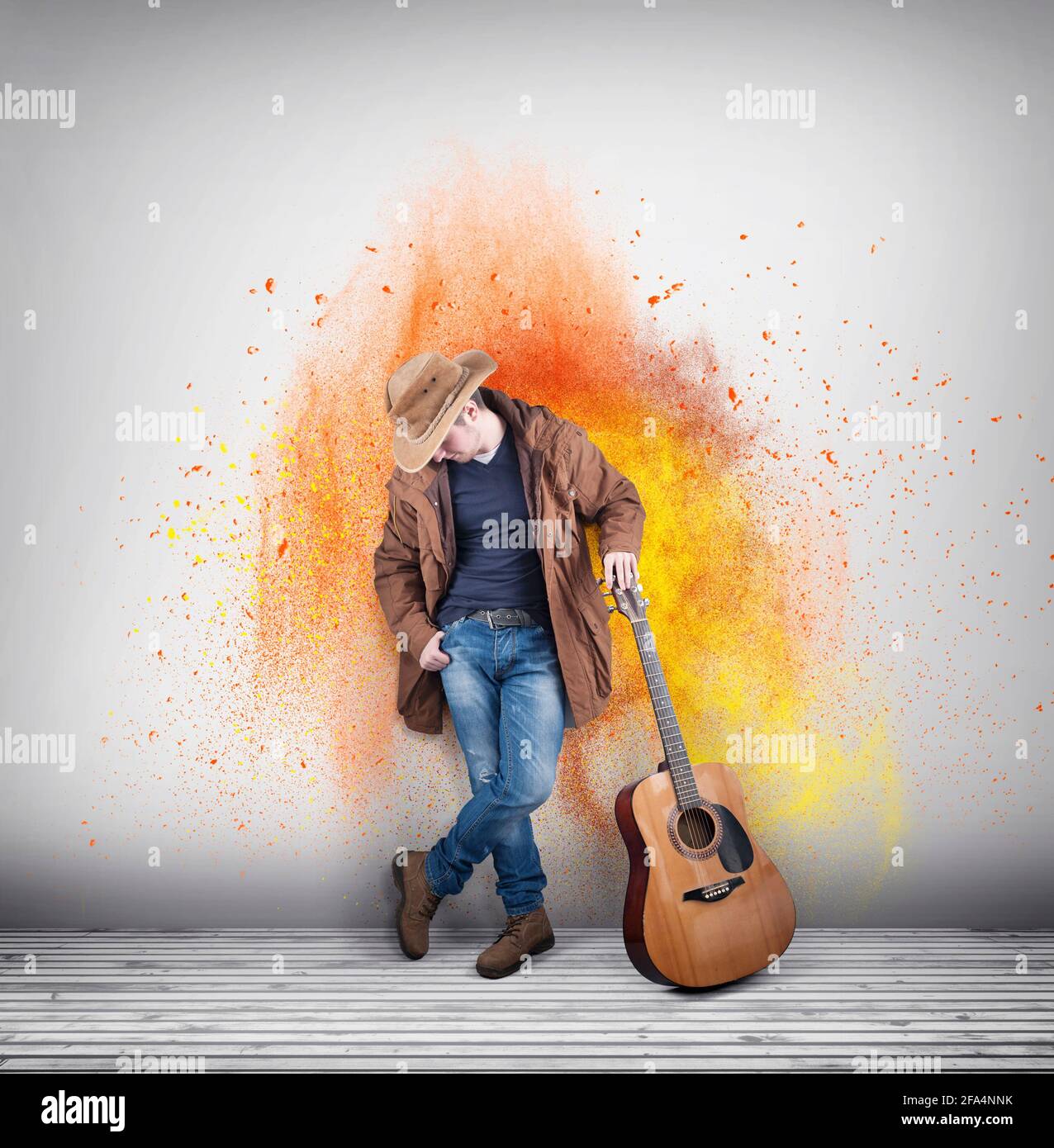 Vaquero con una guitarra acústica contra una pared pintada de colores.  Explosión de polvo Fotografía de stock - Alamy