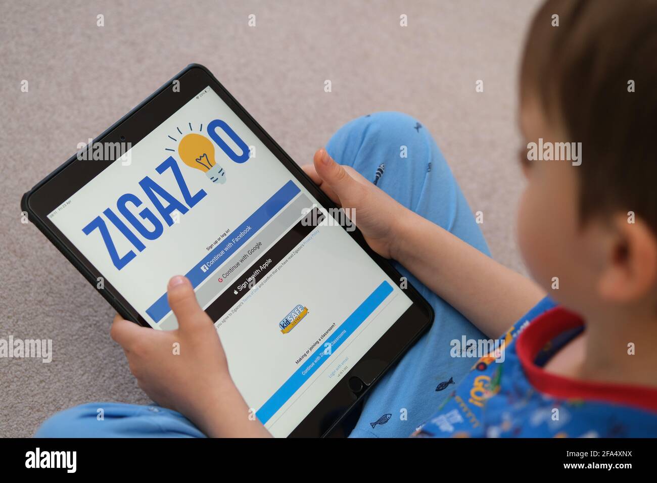 Pantalla de inicio de sesión del sitio web de la aplicación Zigazoo vista en  ipad que está en manos de un niño pequeño. La nueva aplicación es una  plataforma segura para los