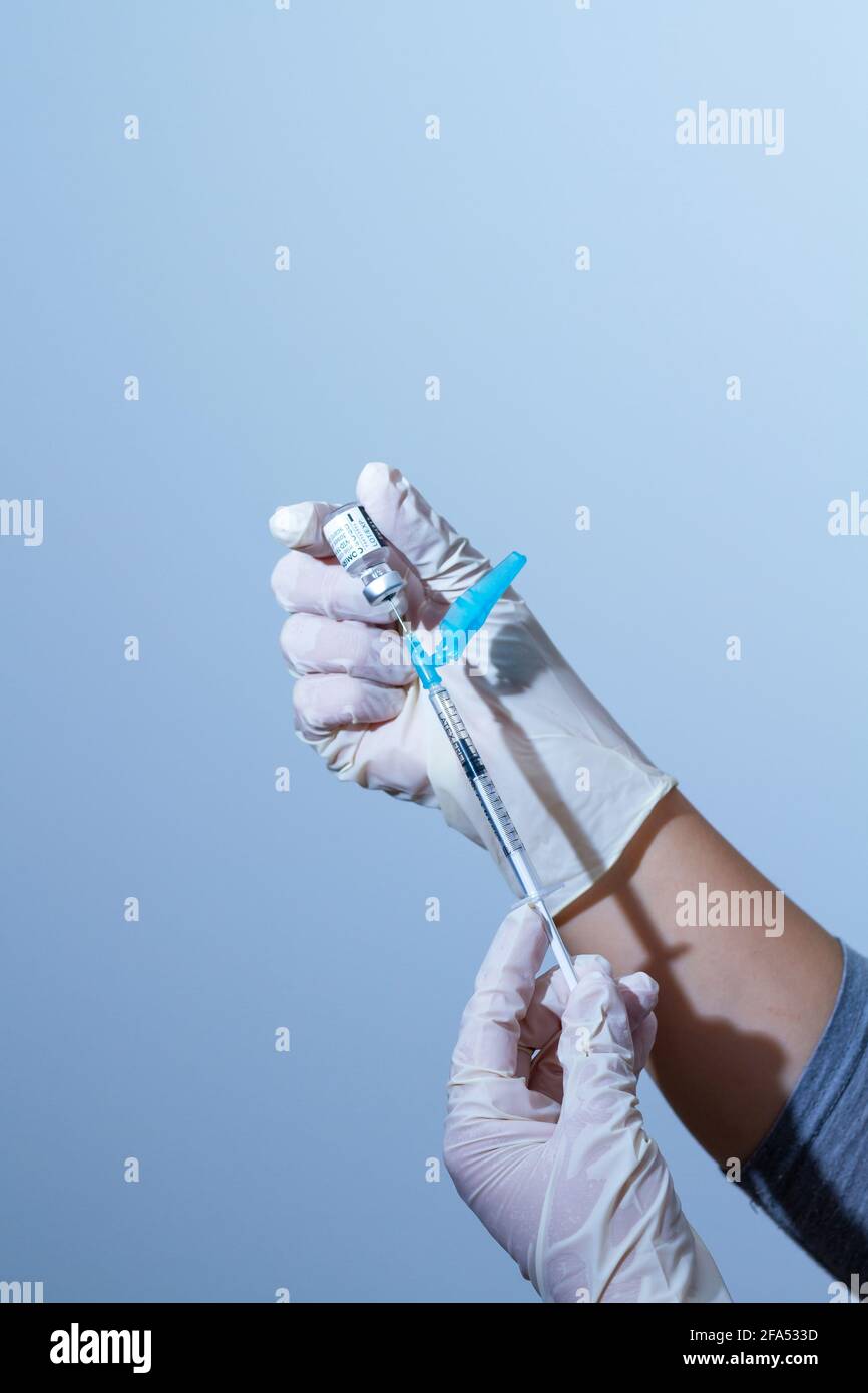Valencia España 21 de abril de 2021. Las manos cubiertas con guantes de látex llevan una dosis de vacuna contra COVID-19 de la compañía farmacéutica Pfizer BioNTec Foto de stock