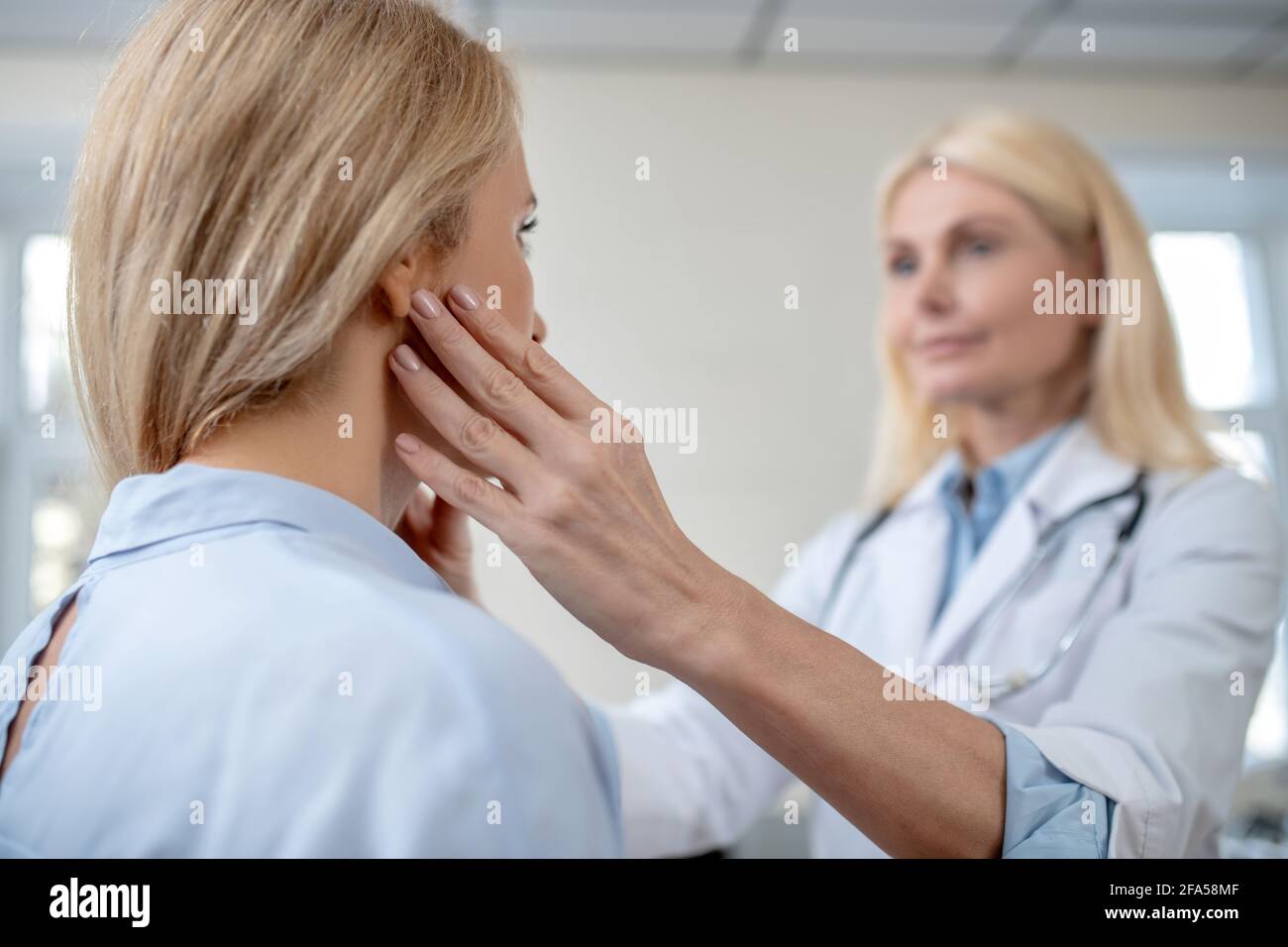 Un médico atento tocando los dedos en la cabeza del paciente Foto de stock