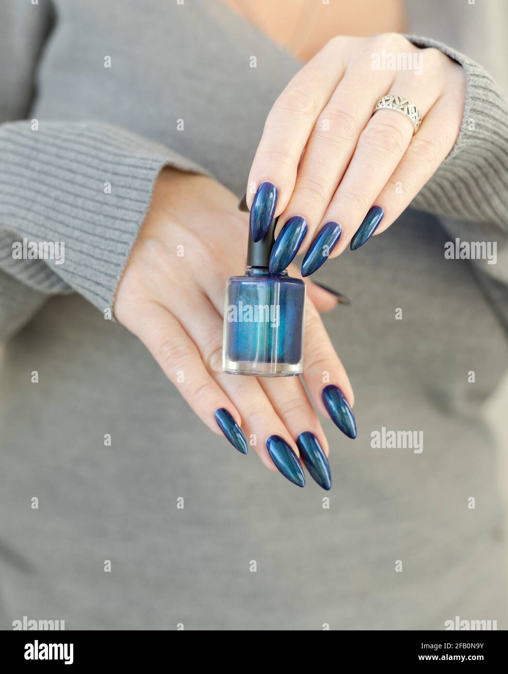 Mano femenina con clavos largos y manicura azul turquesa con botellas de  esmalte de uñas Fotografía de stock - Alamy