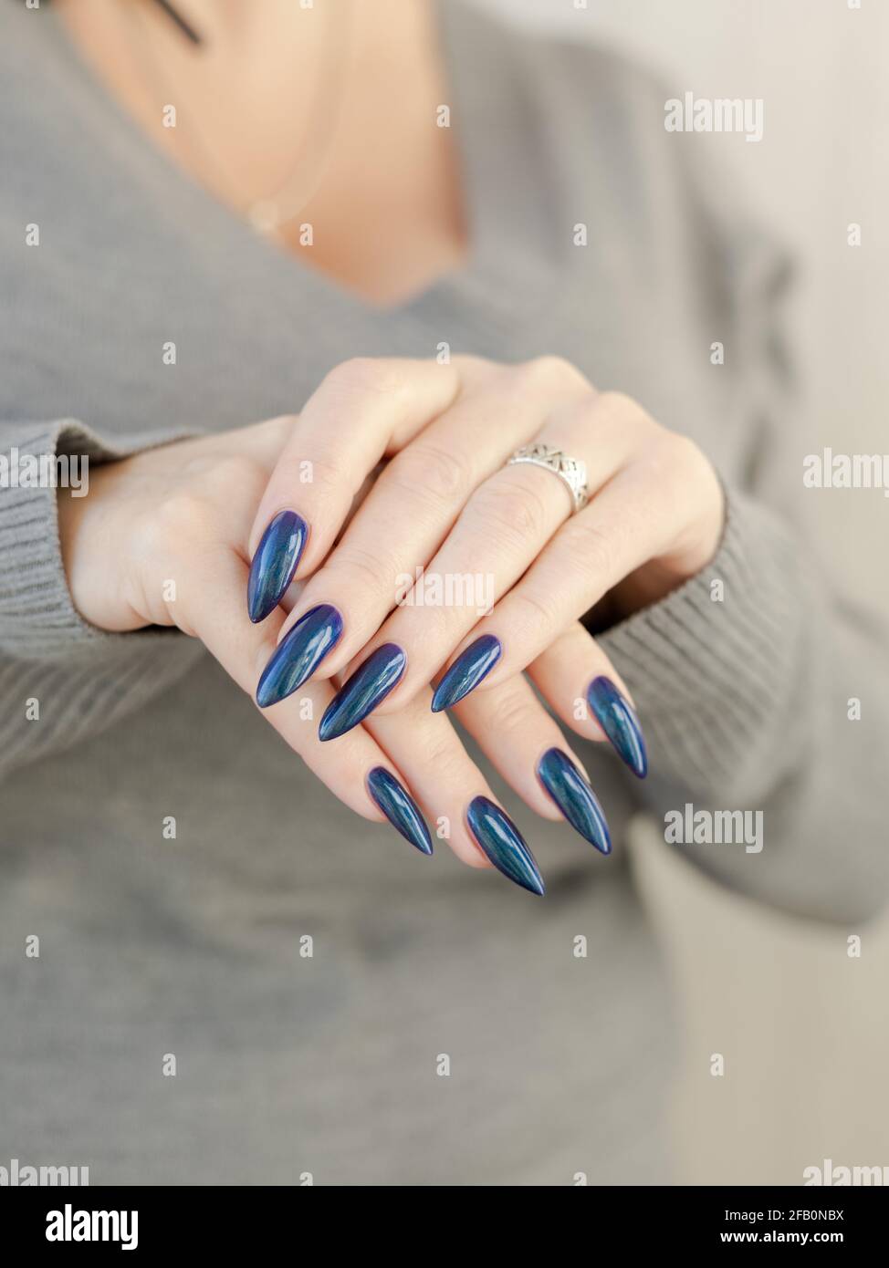 Mano femenina con clavos largos y manicura azul turquesa con botellas de  esmalte de uñas Fotografía de stock - Alamy