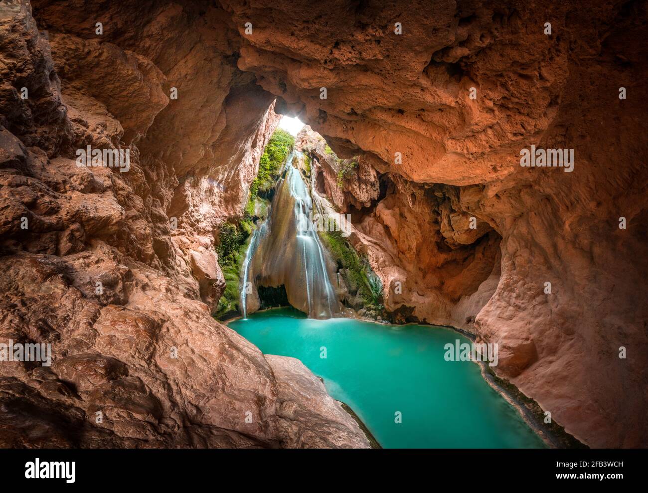 cascada dentro de una cueva y un lago de aguas cristalinas color turquesa. Foto de stock