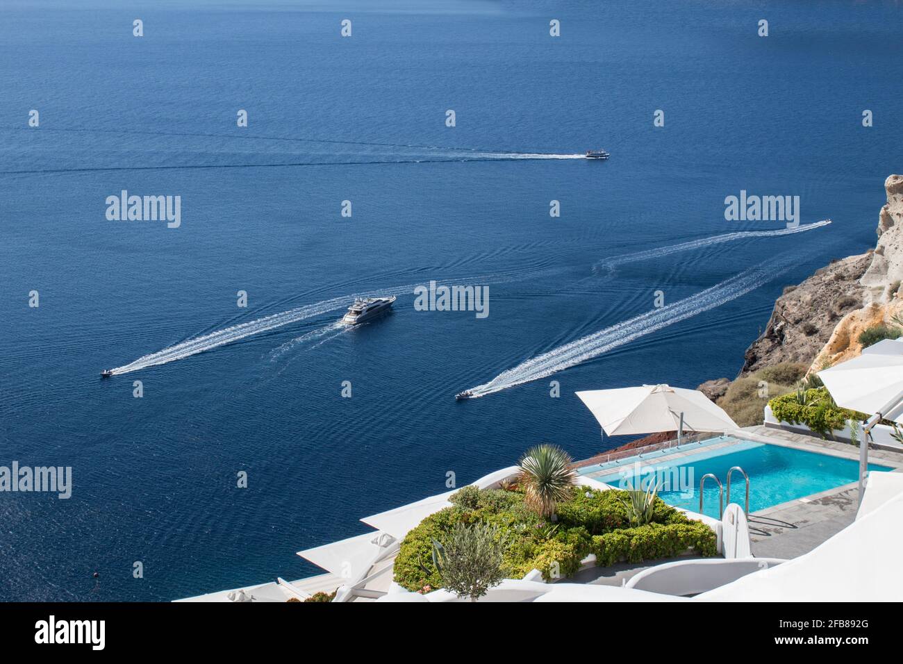 Vista perfecta de Santorini: Piscina en hotel de lujo y yates Foto de stock