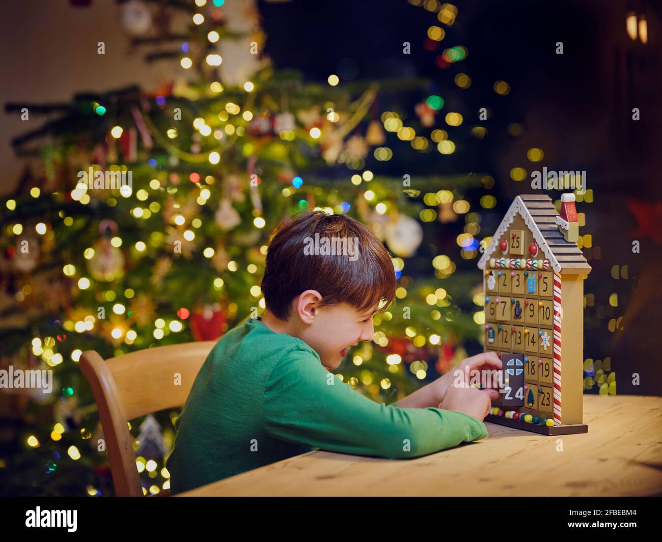 Niño juguetón abriendo Adviento calendario puerta durante la Navidad en casa Foto de stock