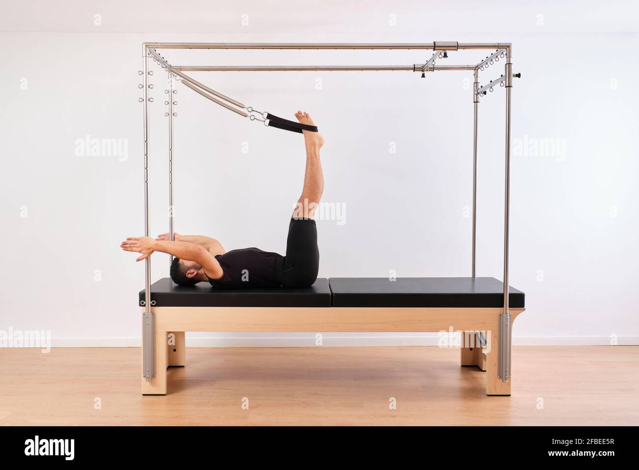 Hombre adulto medio acostado con las piernas levantadas sobre trapecio mesa  mientras practica pilates en el gimnasio Fotografía de stock - Alamy