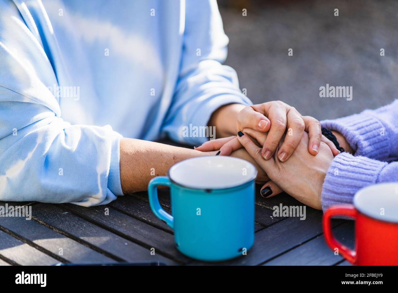 Madre e hija con las manos apiladas sobre la mesa en la parte posterior patio Foto de stock