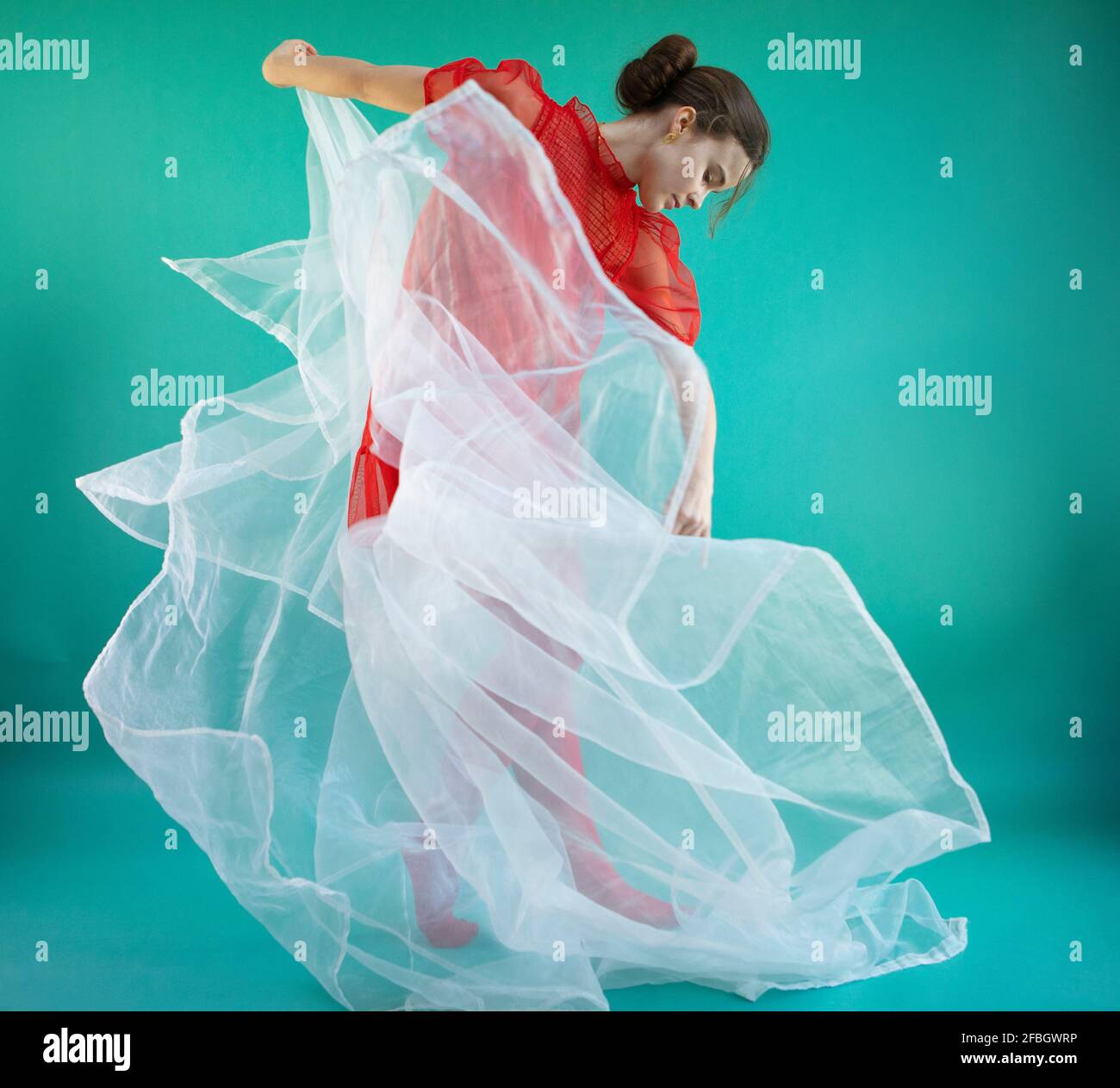 Joven bailarina bailando con tulle blanco sobre fondo turquesa Foto de stock